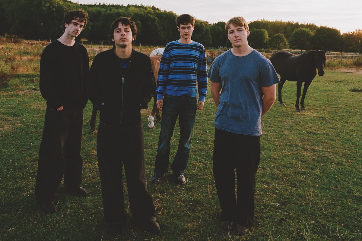 Australian band Radio Free Alice posing outdoors in a grassy field with horses, shot by Imogene Barron.